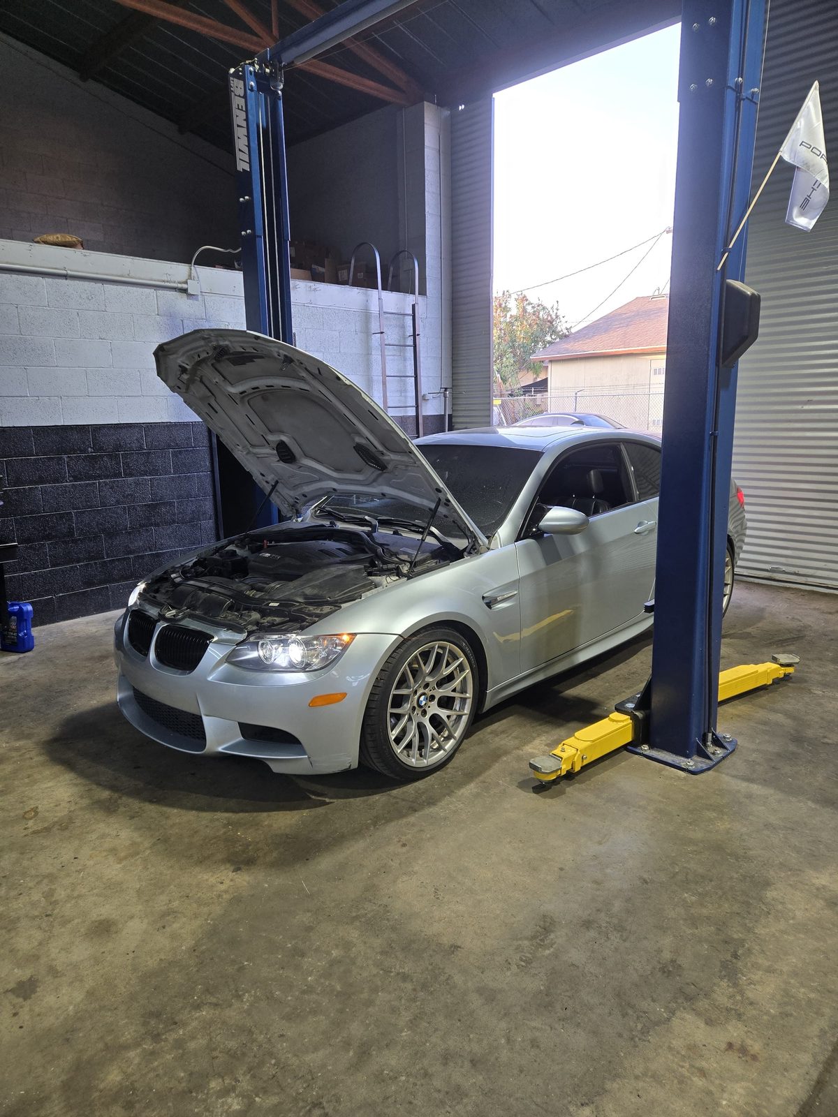 Silver BMW E92 M3 raised on a two-post lift for service