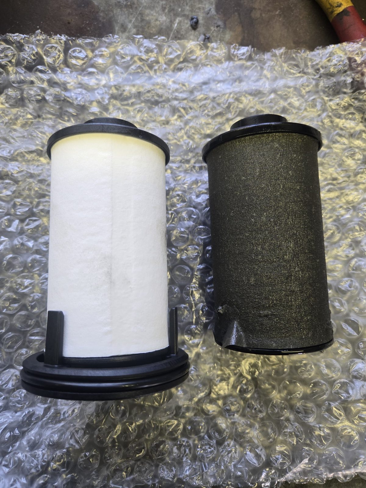 Comparison of a clean new oil filter next to a used dirty filter