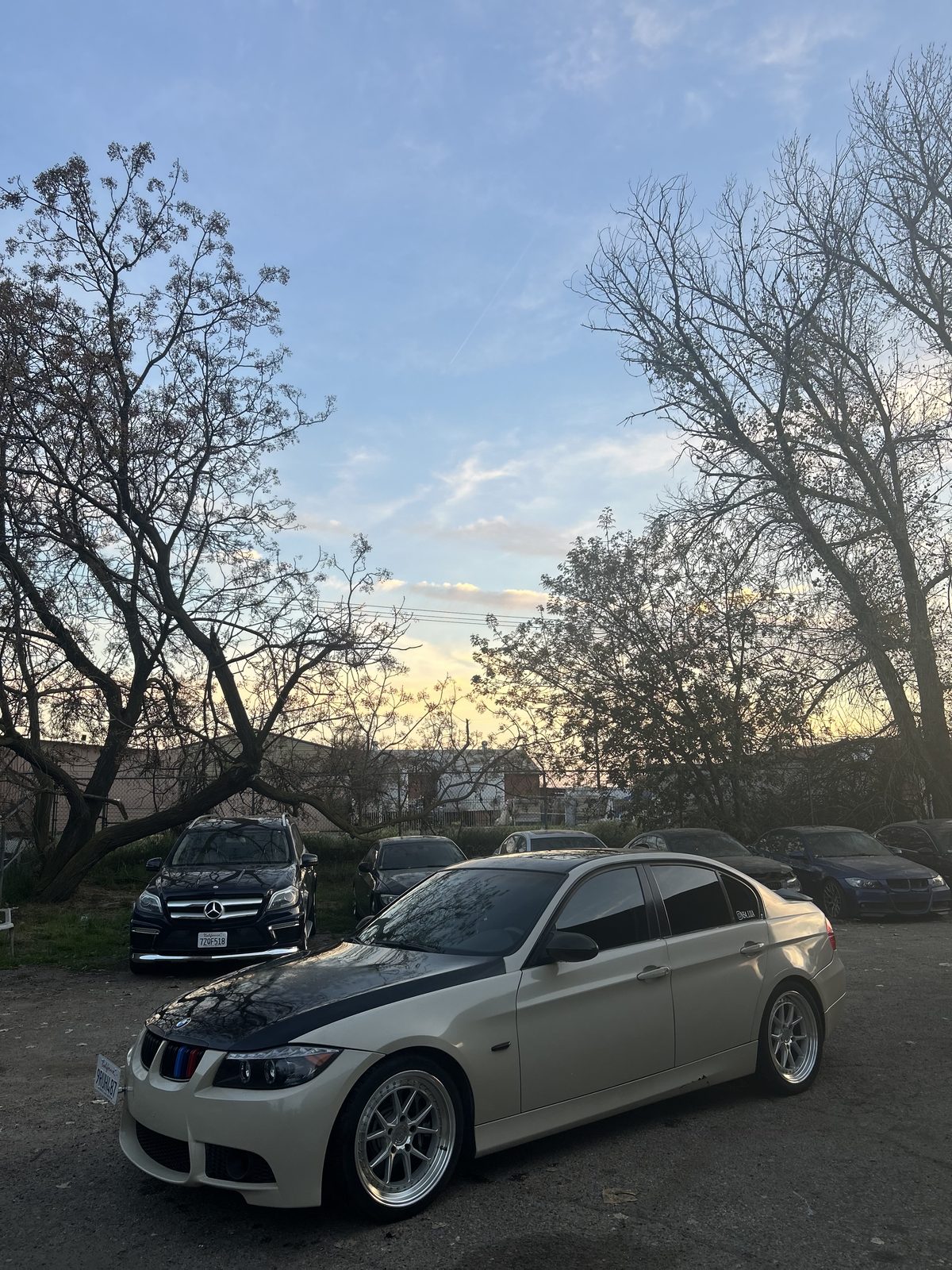 BMW E90 3 Series with M-stripe accents parked at sunset