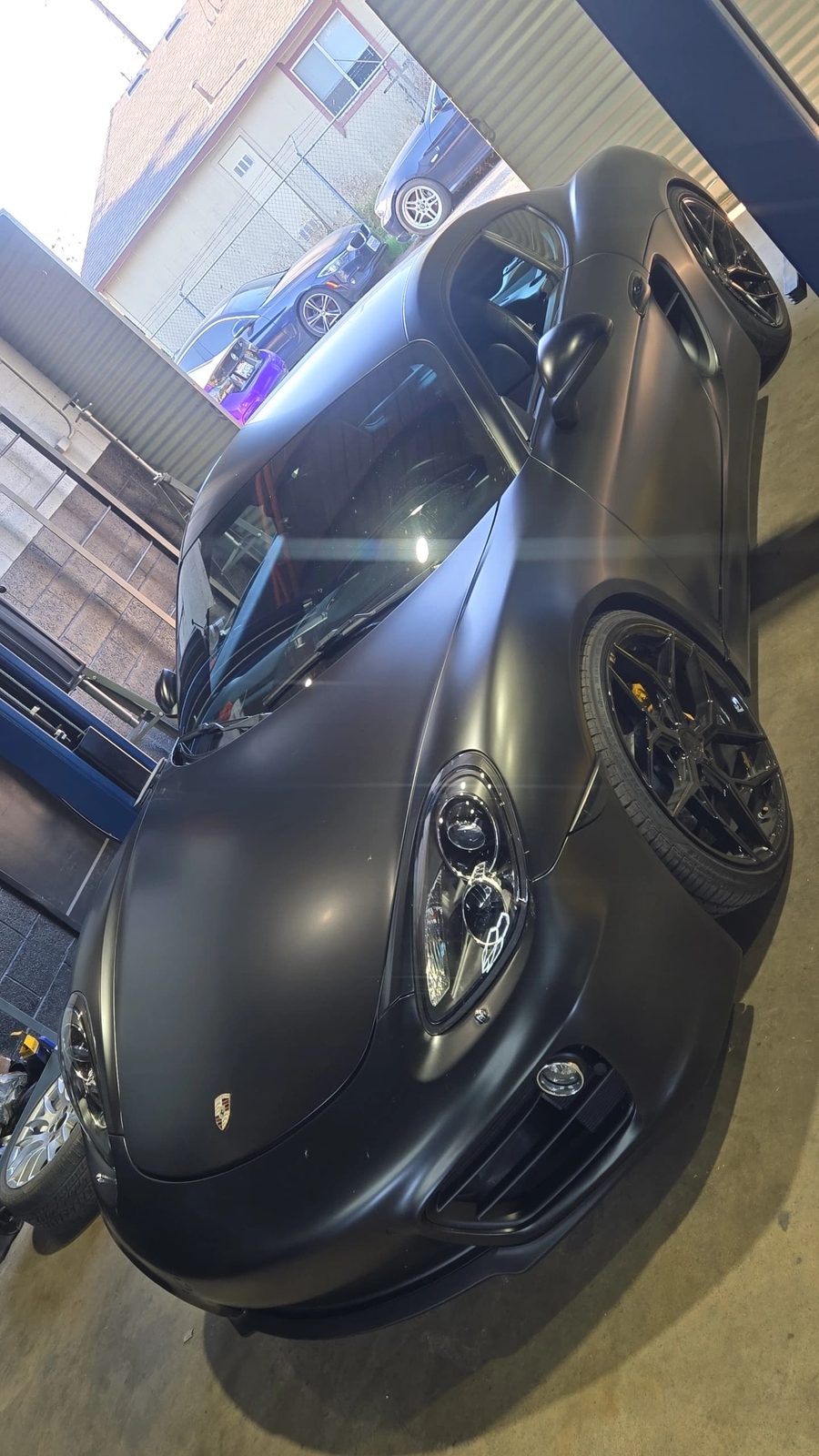 Satin black Porsche 911 with yellow ceramic brakes in the shop